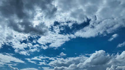 A serene and captivating image of the sky adorned with a dynamic array of clouds. The scene features a wide expanse of blue sky interspersed with fluffy, white cumulus clouds drifting gracefully. The 