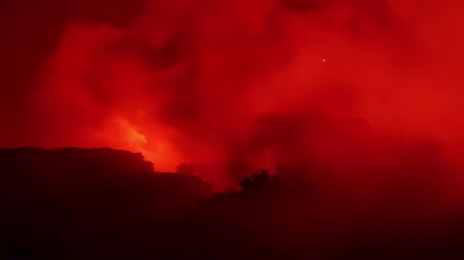 Wall Mural - as the fire rages on the smoke transforms into a deep red haze making it difficult to see through.