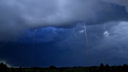 Wall Mural - the storm rages on as lightning erupts from the depths of the dense stormy clouds lighting up the sk
