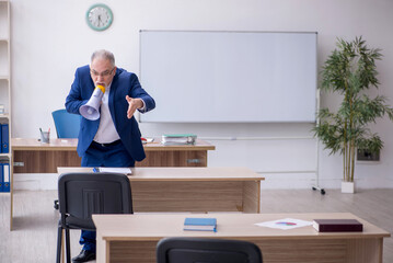 Wall Mural - Old male teacher holding megaphone in the classroom