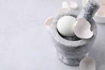 Wall Mural - Broken eggshells, mortar and pestle on grey table, closeup. Space for text