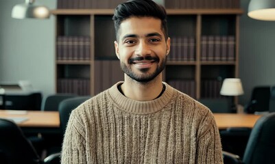 Wall Mural - Portrait of a handsome young man with a beard and mustache in a sweater standing in an office