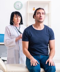 Wall Mural - Young male patient visiting aged female doctor