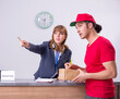 © Elnur - Young male courier delivering box to hotel's reception
