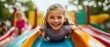 © Thanyaporn - An exciting moment as children slide down a vibrant playground slide, their faces filled with glee. The close-up shot emphasizes their joyful expressions and the slide's colorful design. The