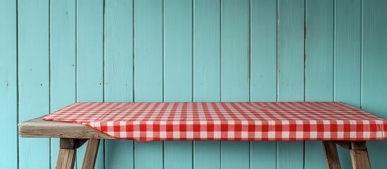 Wall Mural - High quality photo of a wooden deck table with a red checked tablecloth on a mint wallpaper background