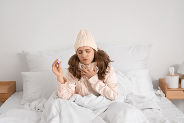 Canvas Print - Ill young woman with thermometer and tissue in bedroom