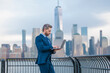 © Volodymyr - Businessman with laptop on financial district streets of New York City. Business in Manhattan. Business man on cityscape in NYC. Business man in suit outdoor. Office worker. Mature business manager.