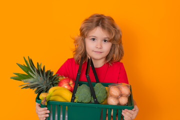 Wall Mural - Food store. Kid with grocery basket, isolated studio portrait. Concept of shopping at supermarket. Shopping with grocery cart. Grocery store, shopping basket.