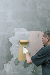 Wall Mural - A man is painting a wall with a roller