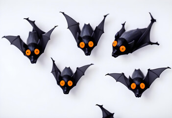 A group of cute cartoon-style black bats with orange eyes against a white background. Halloween season