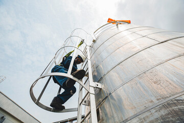 Wall Mural - Male worker climbs up the ladder inspection stainless tank