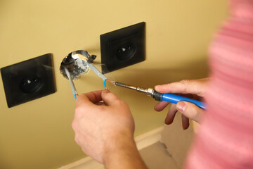 Electrician working on wiring, soldering electrical connections. Man repairing wall sockets. Electrician at work on electrical repairs