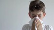 ©  Abyss Photo - Young boy sneezing into a tissue with a plain white background. Represents common cold or allergy symptoms in a clean and simple setting.