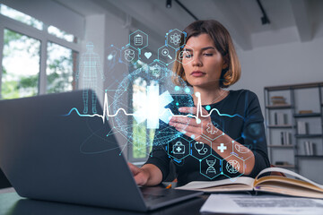 Woman using laptop with futuristic medical hologram in office.