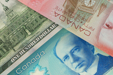 Back of US $100 bill with Canadian dollar banknotes in the background. Foreign exchange market. Financial concept