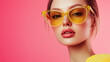 © Brastock Images - Close-up portrait of a woman wearing stylish yellow-tinted sunglasses against a bright pastel background. Ideal for fashion editorials, summer campaigns, and eyewear advertisements.