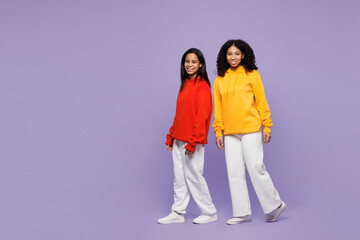 Wall Mural - Full body side profile view two young little kid teen girls women they wear red yellow hoodie casual clothes walking go look camera isolated on plain pastel light purple background. Lifestyle concept.