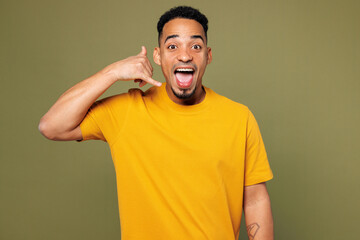 Wall Mural - Young man of African American ethnicity he wears yellow t-shirt casual clothes doing phone gesture like says call me back isolated on plain pastel green background studio portrait. Lifestyle concept.