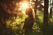 © StockUp - Silhouette of a woman standing in a sunlit forest, surrounded by lush green plants and trees at sunset.