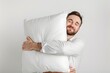 © Igor - man hugging pillow isolated on flat white background with copy space. Bedding store banner template