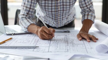 Young adult architect sketching blueprints at a desk