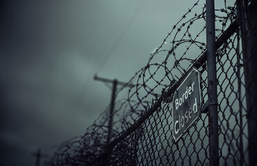 border closed sign, on a chain link fence with razor wire, protecting borders, immigration concept