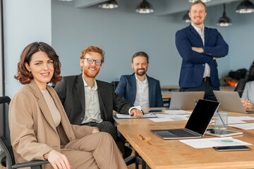 Aufkleber - A diverse team of four professionals sits around a conference table in a modern office space. They appear to be in the midst of a successful business meeting.