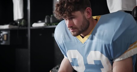 Wall Mural - Serious man, football player and team captain with ball in locker room for match, game or half time. Young male person or athlete getting ready or preparation for sports tournament or competition