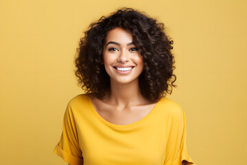 Poster - beautiful female model wearing yellow shirt smiling looking into the camera on yellow background, portrait of a woman