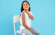 © Prostock-studio - Vaccination Of Children. Happy Vaccinated Kid Girl Showing Arm With Adhesive Bandage After Vaccine Injection Sitting On Blue Studio Background. Kids And Covid-19 Prevention, Antiviral Immunization