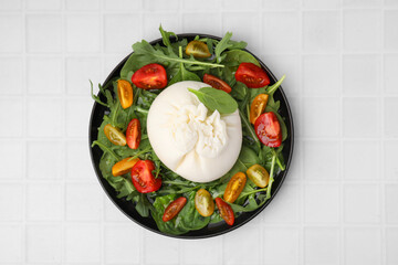 Delicious burrata salad on white tiled table, top view