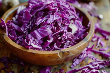 Wall Mural - Sliced red cabbage filling a wooden bowl, sitting on a rustic table with more cabbage scattered around