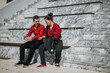 © qunica.com - Young business colleagues wearing matching red shirts, sitting on marble stairs while having a casual conversation in the city on a sunny day.