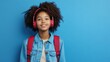 © Master old - Young african american girl teen student in denim clothes, backpack headphones isolated on blue wall background studio portrait. Education in high school university college concept. Mock up copy space