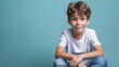© Preecha - Young boy casually sitting on a solid color background, highly detailed photograph