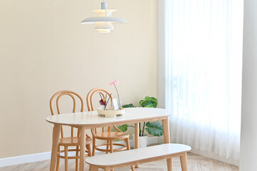 Poster - Modern dining area with wooden chairs, a bench, and a white table in a bright, cozy room.
