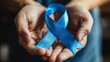 © Pavel Kachanau - A person holds a blue ribbon representing diabetes awareness and support