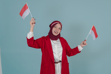 Happy Indonesian woman wearing a red jacket and hijab holding two mini country flags.