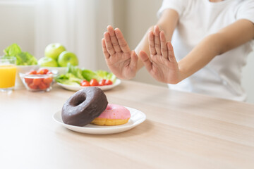 Wall Mural - Diet, dieting asian young woman, girl hand push out, refuse, deny sweet donut, dessert doughnut on plate, choose green apple and vegetable salad, eat food for good healthy, female getting weight loss