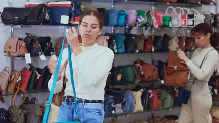 Canvas Print - Young woman in casual clothes chooses handbag in store