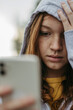 © Halfpoint - Portrait of teenage girl looking at her smartphone, sad, anxious, alone. Cyberbullying, girl is harassed, threated online.