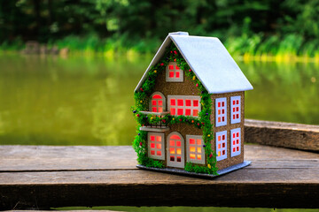 Decorated brown house with gradient red light in windows against forest and lake background