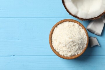 Wall Mural - Fresh coconut flour in bowl and nut on light blue wooden table, top view. Space for text