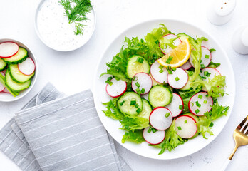 Wall Mural - Summer vegan crispy salad with cucumbers, radishes and lettuce, white background, top view