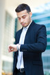 © Minerva Studio - Punctual businessman checking wristwatch outdoors