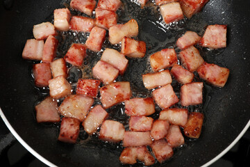 Wall Mural - Pieces of bacon frying in pan, top view