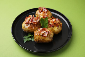 Wall Mural - Delicious baked potatoes with bacon and parsley on green background, closeup