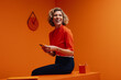 © Jacob Lund - Mature business woman using mobile phone in vibrant, monochromatic orange studio environment
