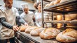 © hobonski - A team of bakers proudly displays a batch of freshly baked artisan loaves in a warm, inviting bakery setting. The golden crusts and rustic textures capture the essence of traditional baking.